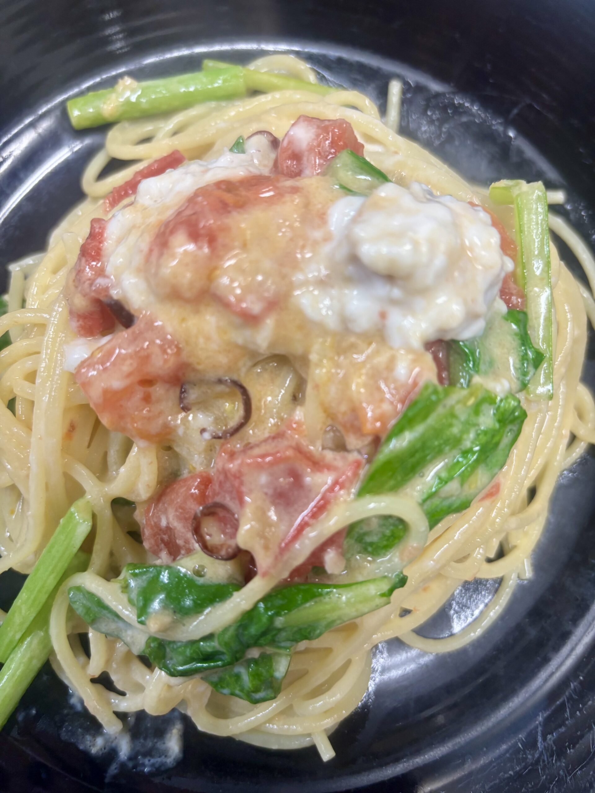 クリーミーな白子が溶け込むソースに、ほうれん草とトマトが彩りを添えたスパゲッティ。まろやかな旨みと新鮮な具材が絡む濃厚パスタのアップ写真